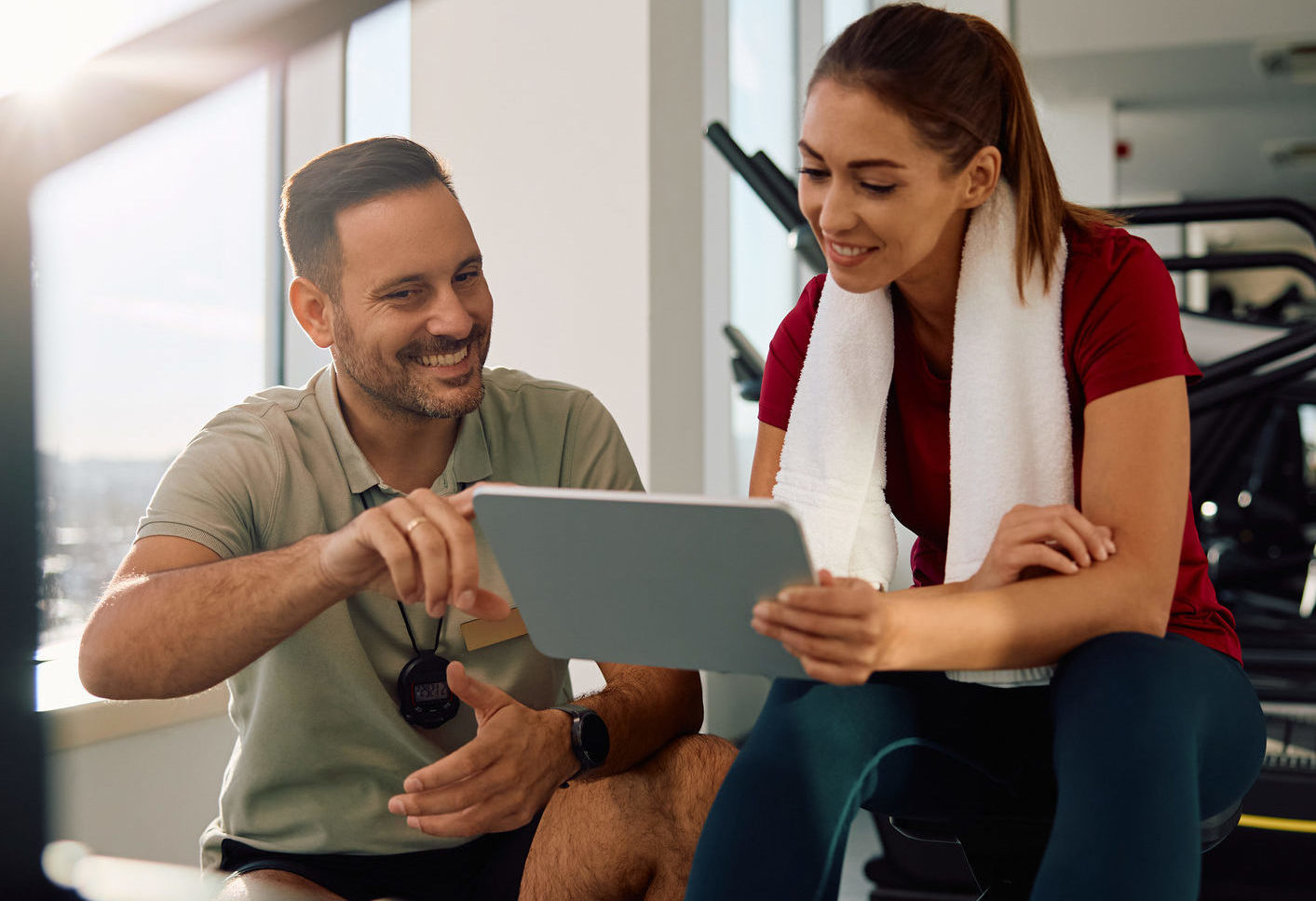 Happy fitness instructor and sportswoman analyzing workout plans during sports training in a gym. Massage sportif Kinésport