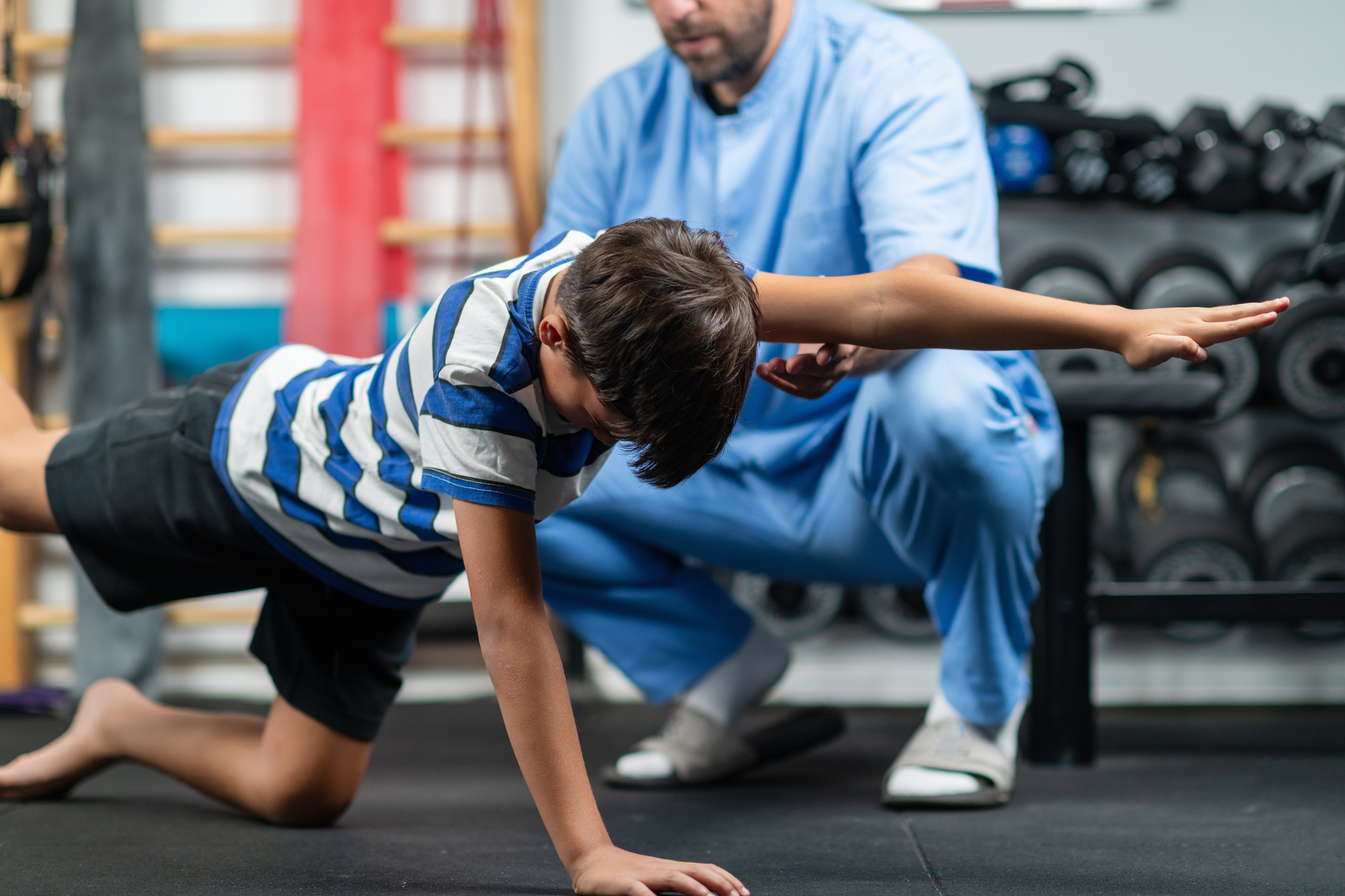 Physical therapist guiding a young boy through exercises for stability and balance, aimed at improving coordination and strength in a supportive rehabilitation session personal coaching