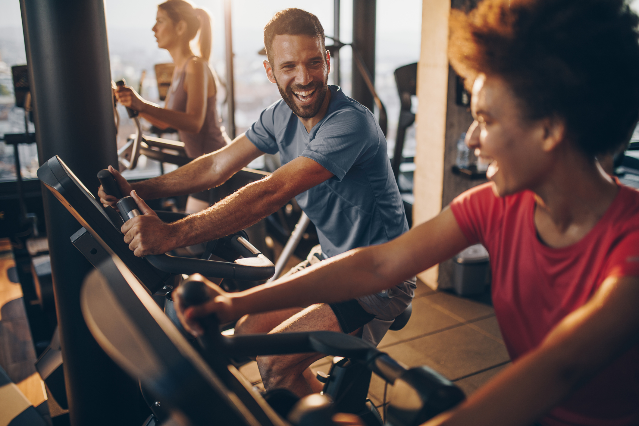 Cheerful male athlete talking to his friend on exercising training in a health club. Biking Soft
